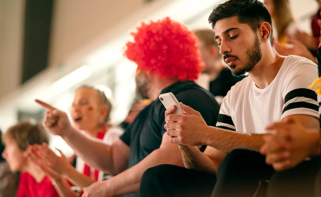 Two fans, one with a red wig, watching a game.