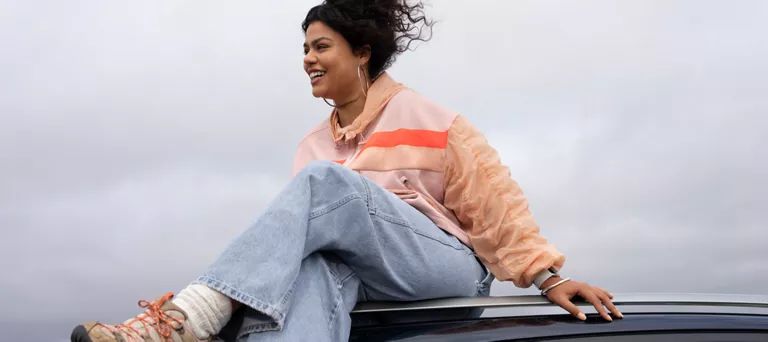 woman sitting on top of her car