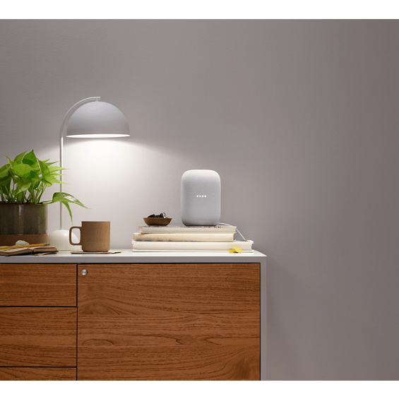 Lifestyle view of Google Nest Audio in chalk on dresser under lamp