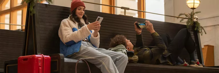 travelers using their phones on a bench