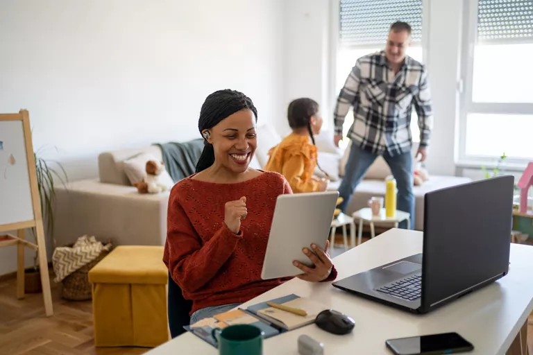 Woman holding a tablet with family in the background