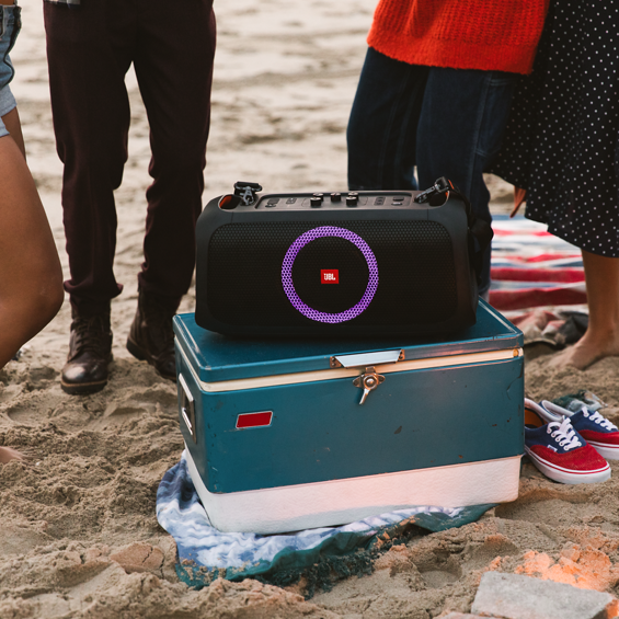 View of a JBL Party Box On-The-Go on top of a cooler at the beach.