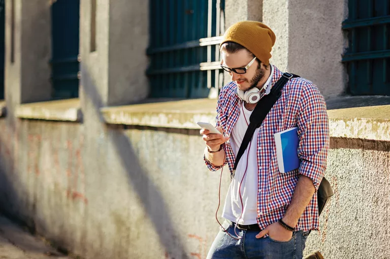 Male with headphones and smartphone outdoors
