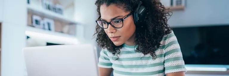 Woman looking at her computer screen with headphones